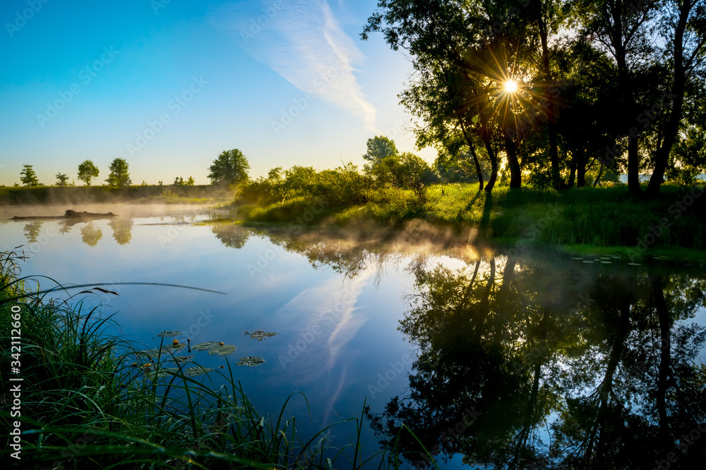 Magical morning on the river. Fog above the water and the sun with rays through the trees. Magical morning on the river. Fog above the water and the sun with rays through the trees.