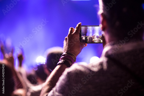 Manos sujetando teléfono móvil grabando un festival de música