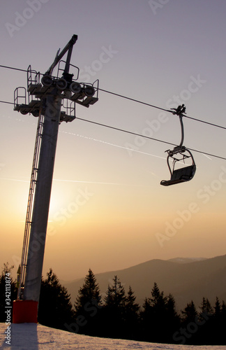 Ski lift chair on ski slope at sunset