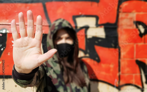 Coronavirus and air pollution concept. The girl wears a protective mask to protect against coronavirus and shows a stop hand gesture to stop the outbreak of the corona virus.