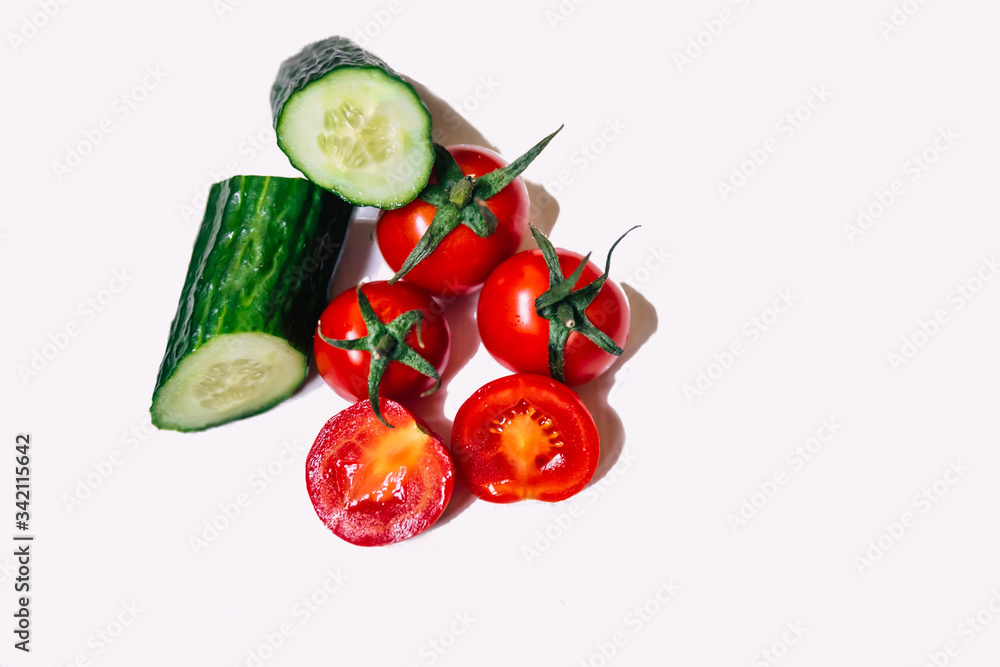 Red cherry tomatoes with cucumber isolated on white background.