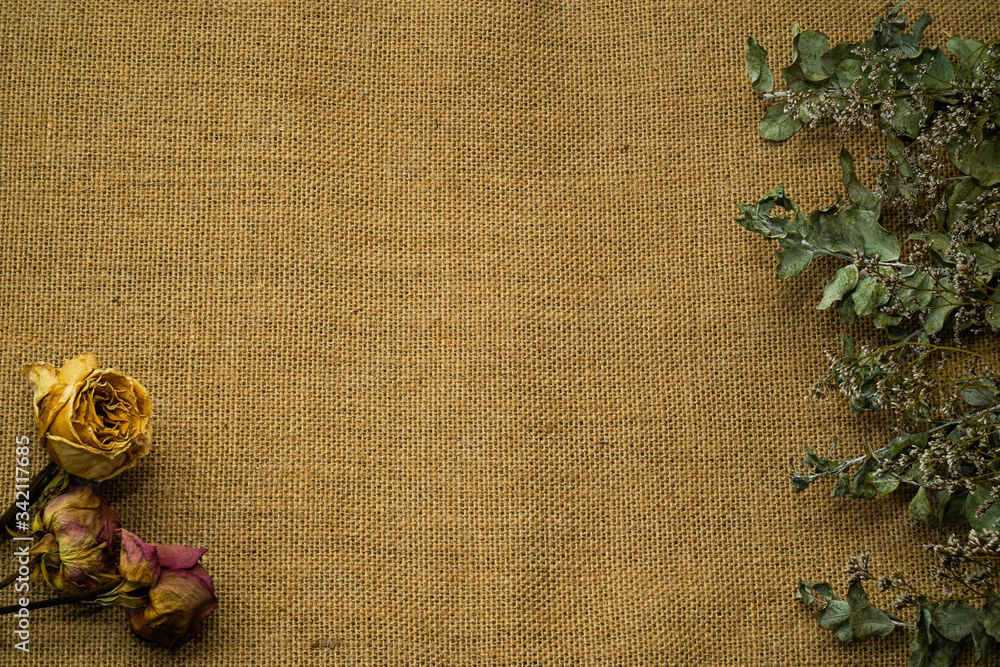 Dried roses and dry rose leaves lie on burlap background Dried roses and dry rose leaves lie on burlap background