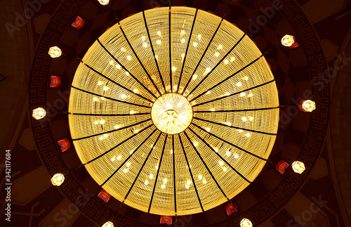 A beautiful massive intricate chandelier hanging in the middle of the dome of Al Fateh Grand Mosque . Al Fateh mosque is one of the largest mosque in the world photo