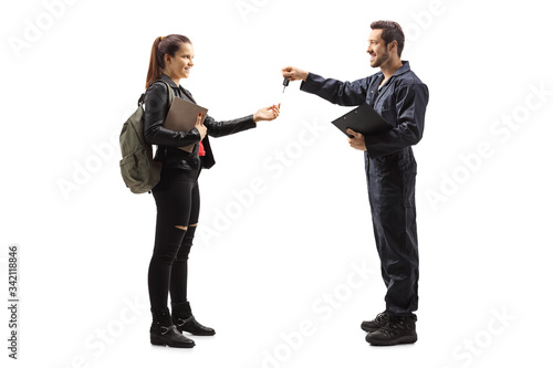 Auto mechanic giving car keys to a young female