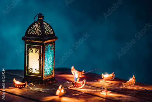 Ramadan Lantern with Colorful Light Glowing at Night and Glittering with Bokeh Lights on Ground. Festive Greeting Card, Invitation for Muslim Holy Month Ramadan Kareem. Blue Dark background