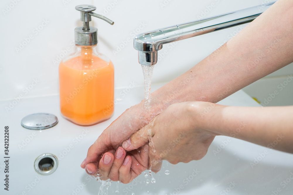 Hand washing with soap. Girl washes her hands with antibacterial soap for the prevention of coronavirus covid-19 2019-ncov and flu. Sink, faucet, hands and soap. Minimalist bathroom Hand washing with soap. Girl washes her hands with antibacterial soap for the prevention of coronavirus covid-19 2019-ncov and flu. Sink, faucet, hands and soap. Minimalist bathroom