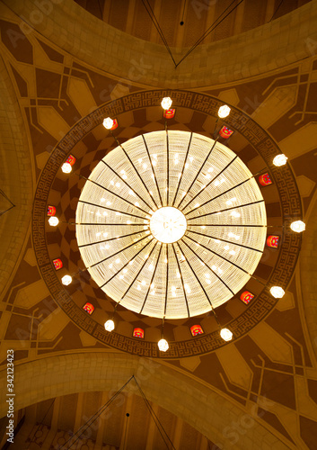 A beautiful massive intricate chandelier hanging in the middle of the dome of Al Fateh Grand Mosque . Al Fateh mosque is one of the largest mosque in the world photo