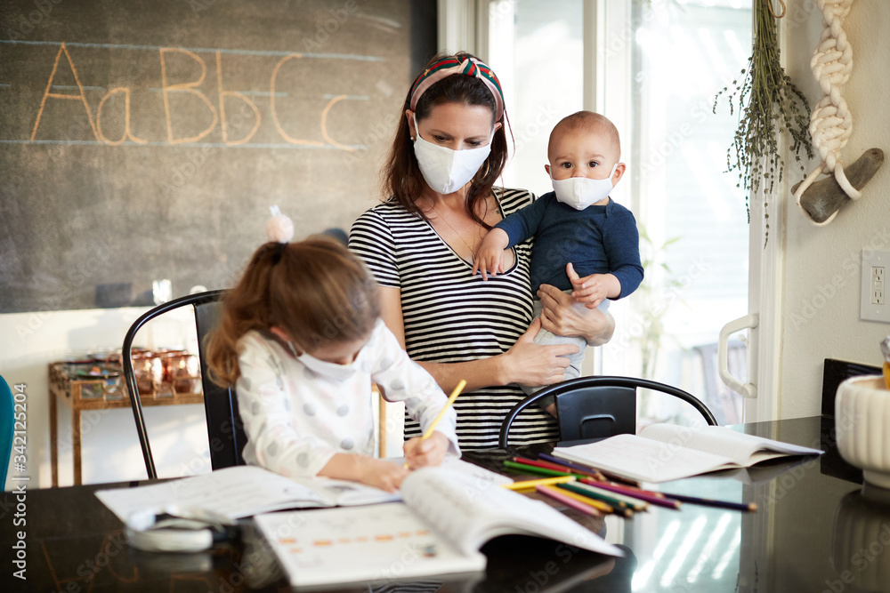 Obraz premium A mother and son help a daughter do homework wearing a mask
