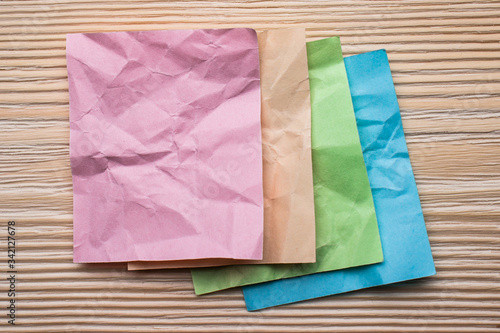 Several multi colored crumpled sheets of paper on a wooden surface.