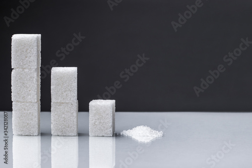 The downward chart is made up of sugar cubes and granulated sugar. Sugar reduction in consumption сoncept.