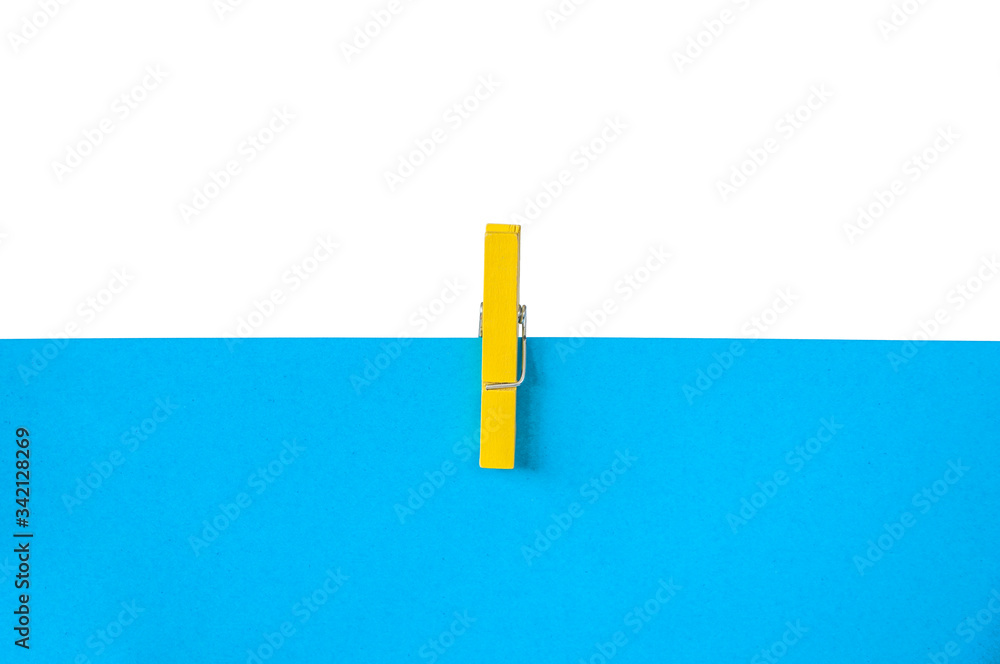 yellow clothespin on blue paper. azure and white background yellow clothespin on blue paper. azure and white background