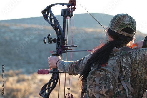 Female archery hunter drawing bow