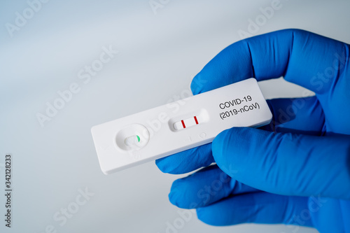 Doctor holding a Positive Result for COVID-19 with test kit for viral disease COVID-19 2019-nCoV. Lab card kit test for coronavirus SARS-CoV-2 virus. Fast test COVID-19. photo