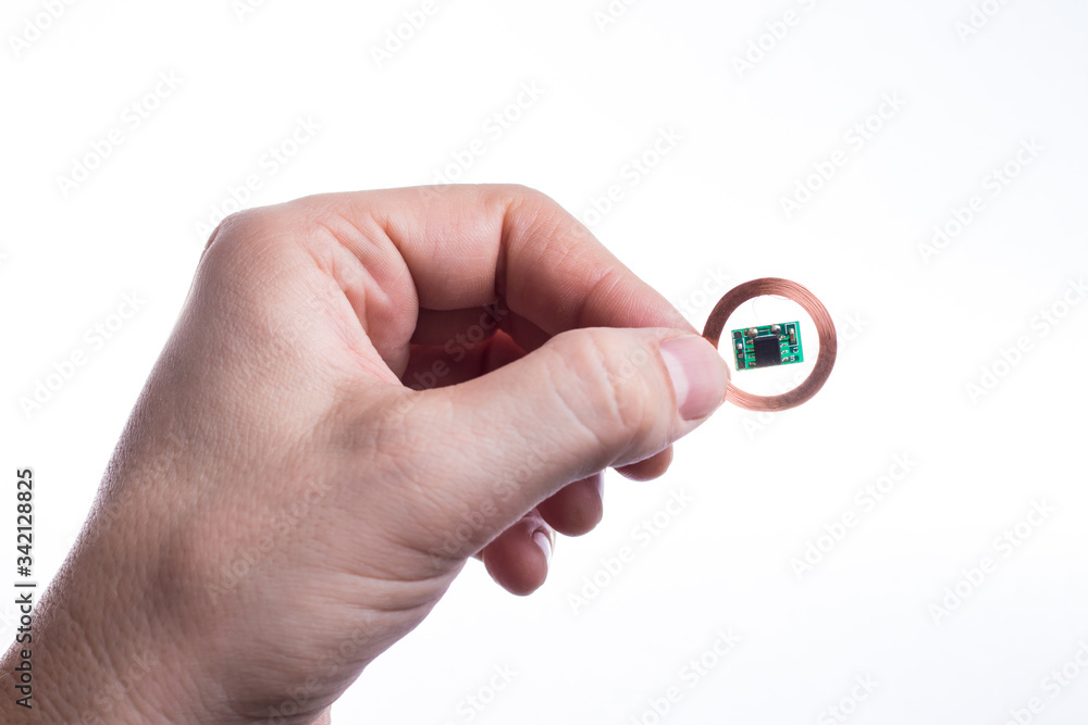 A person holds a radio frequency identification chip in his hand. A person holds a radio frequency identification chip in his hand.