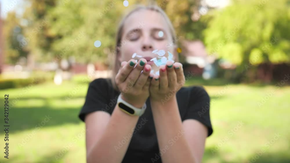 Teenager girl blows multicolored confetti from her hands. Teenager girl blows multicolored confetti from her hands.
