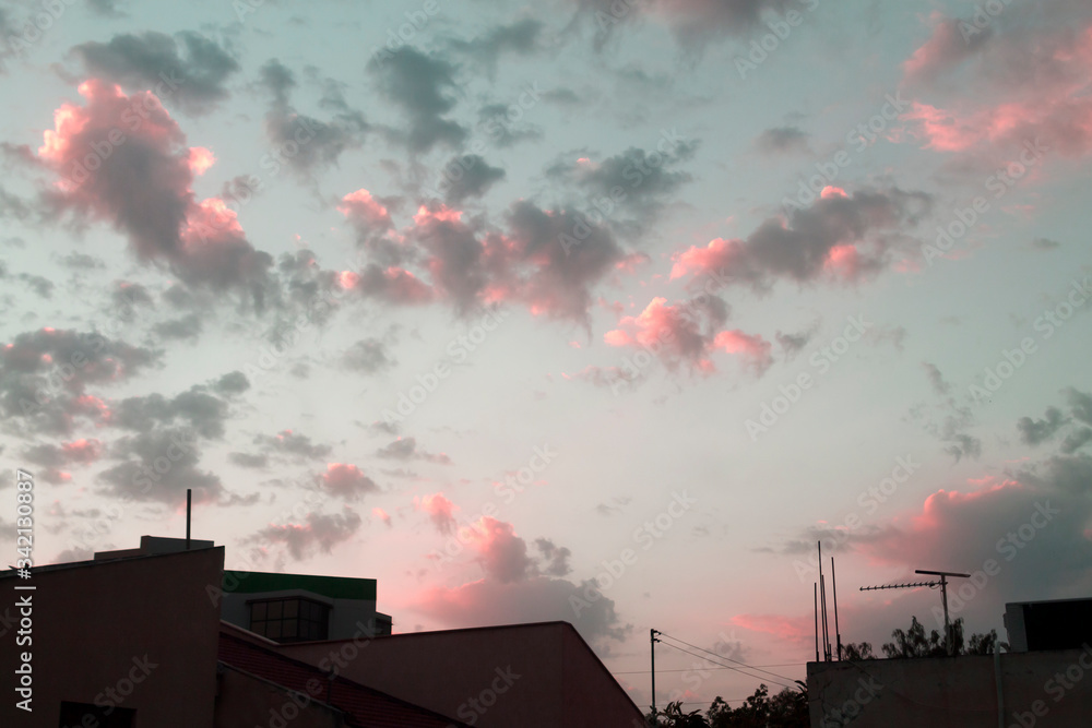 Gray and pink clouds above rooftops at sunset Gray and pink clouds above rooftops at sunset