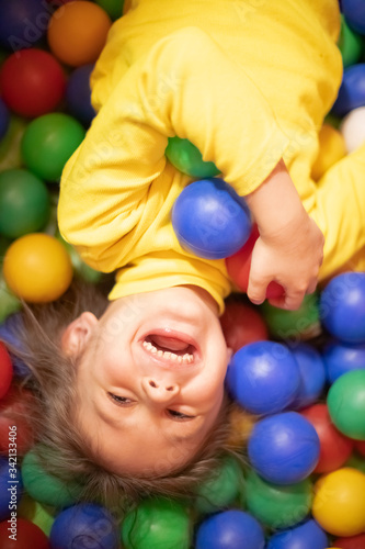Little girl in a ball pit smiling at the camera, having fun at the children play center