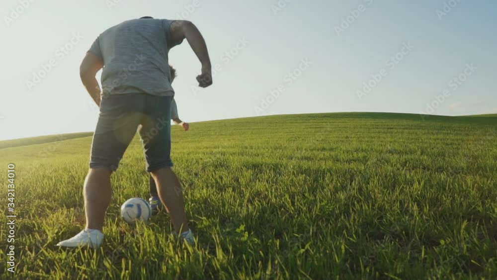 Father and his son playing together soccer football on field. Father and his son playing together soccer football on field.
