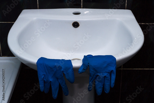 Blue rubber gloves on the sink. Bathroom cleaning.