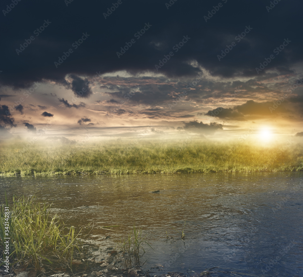 Graslandschaft mit Fluss bei Sonnenuntergang