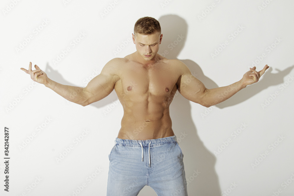 Muscle strong beautiful stripped male model in  blue denim jeans on white isolated font background with shadow