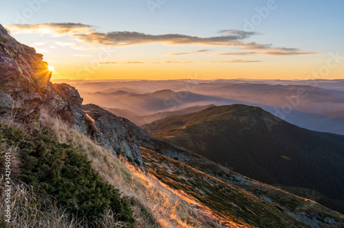 Very beautiful sunrise in the mountains. Early sunbeams in the mountains. Beautiful mountainous terrain. © vzwer