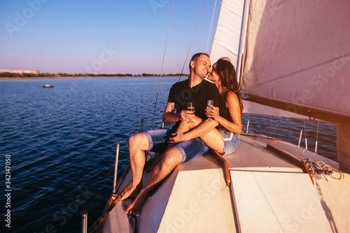 Couple on the sailing boat drink champagne in a sea at sunset © VlaDee