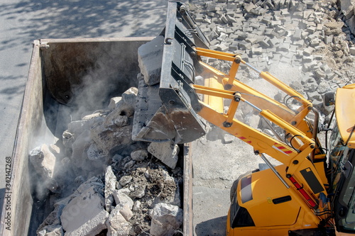 Bulldozer loader uploading concrete debris into dump truck