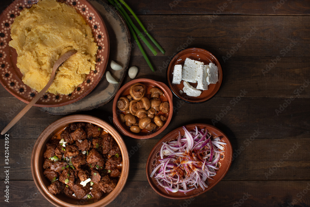 Traditional Eastern European corn mush (mamaliga, polenta, banosh, balmes) served with side dishes and vegan seitan Traditional Eastern European corn mush (mamaliga, polenta, banosh, balmes) served with side dishes and vegan seitan