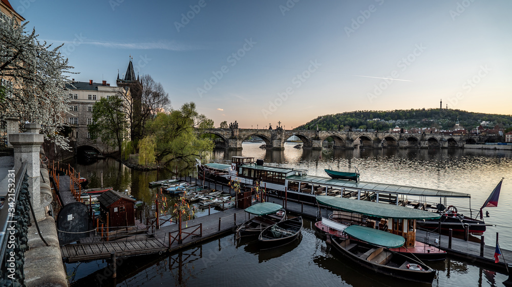 Charles Bridge and Vltava river with boats parked on the riverside in Czechia. Beautiful panoramic view.  Photo of Prague historical city center. 