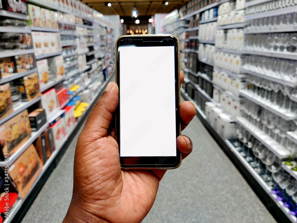 A hand holding a mobile phone in a supermarket. A hand holding a mobile phone in a supermarket.