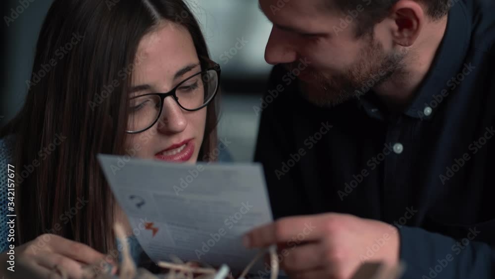 Close-up young sweet romantic Caucasian couple reading post card after receiving holiday gift box shipping slow motion. Close-up young sweet romantic Caucasian couple reading post card after receiving holiday gift box shipping slow motion.