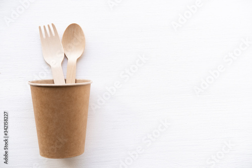 eco friendly disposable kitchenware utensils on white background. wooden forks and spoons in paper cup. ecology, zero waste concept. top view. flat lay.