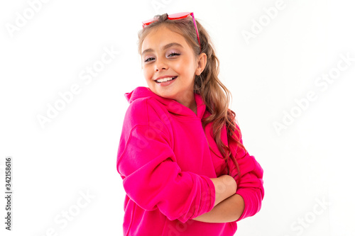 Fashionable teenager girl in pink hoody and with pink sunglasses gesticulates, portrait isolated on white background