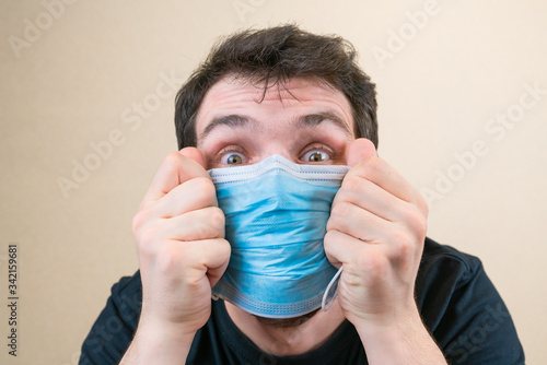 Young man in blue protective medical mask and happu with it. Self-isolation and quarantine. Stay home photo