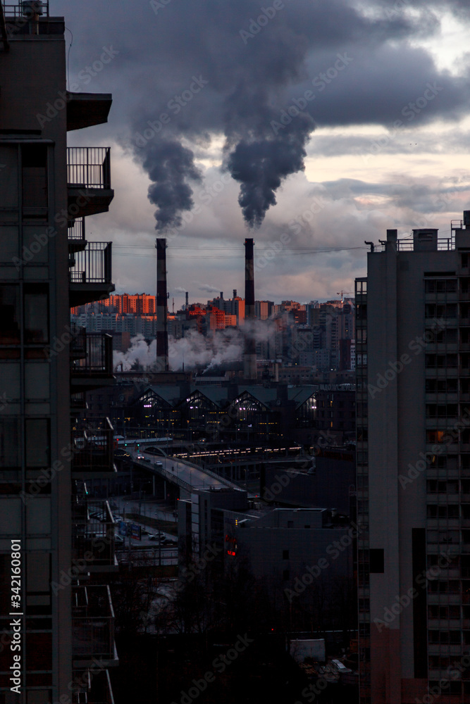 Environmental and air pollution, ecological problems concept. Smoke from factory chimneys against a gray cloudy sky. Urban landscape.