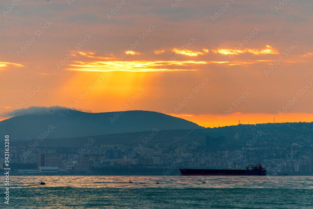 Cargo ship sailing the sea at a golden sunset or sunrise. Ocean shipment across water as the sun sets or rises. Harmony and beauty in nature. Scenic peaceful sea view Cargo ship sailing the sea at a golden sunset or sunrise. Ocean shipment across water as the sun sets or rises. Harmony and beauty in nature. Scenic peaceful sea view