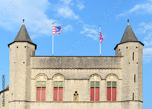 Exit side of the Kruispoort (gate to Saint Cross) with flags of Bruges against blue sky with white fluffy clouds. One of the four remaining original entrance gates to the inner city of Bruges photo