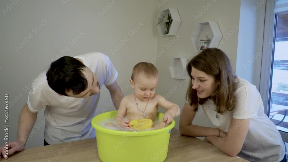 Parents bathe their daughter in a small bath Parents bathe their daughter in a small bath