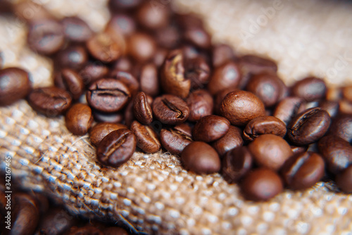 Bag of roasted coffee beans on a dark background with burlap fabric  close view. Coffee beans background. Coffee beans close-up  selective focus  shallow depth of field.