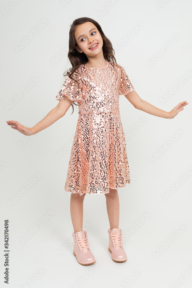 Full-length teenager girl in shiny party dress posing on a white studio background Full-length teenager girl in shiny party dress posing on a white studio background