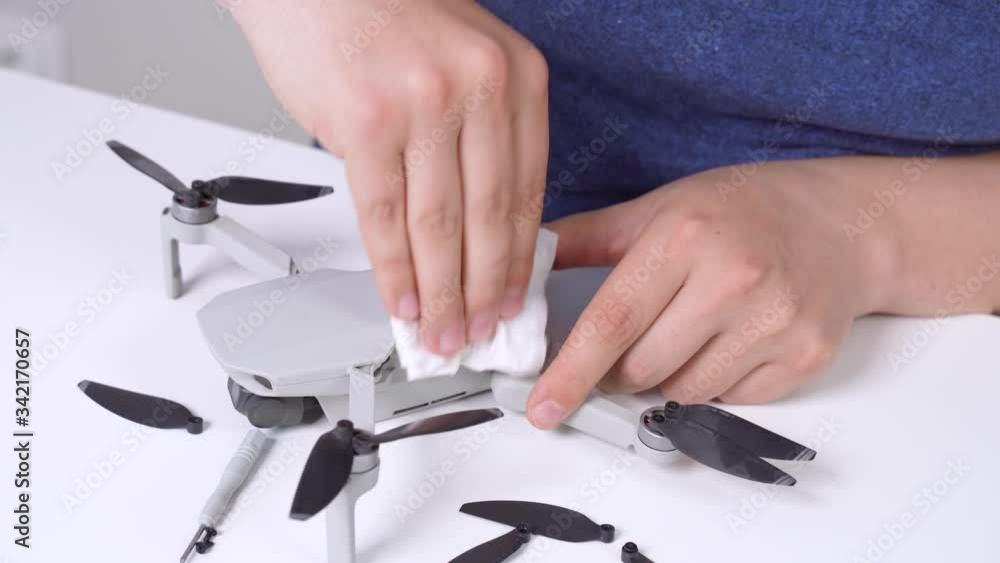 Human hands wipe drone with sterile paper towel impregnated with cleaning disinfectant solution from dirt and dust. Service for maintenance of electronics and robotics. Repair of gadgets at home. Human hands wipe drone with sterile paper towel impregnated with cleaning disinfectant solution from dirt and dust. Service for maintenance of electronics and robotics. Repair of gadgets at home.