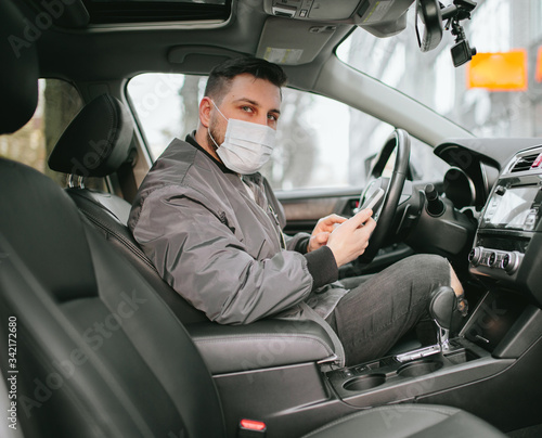 Young man driver in car vehicle wearing medicine mask
