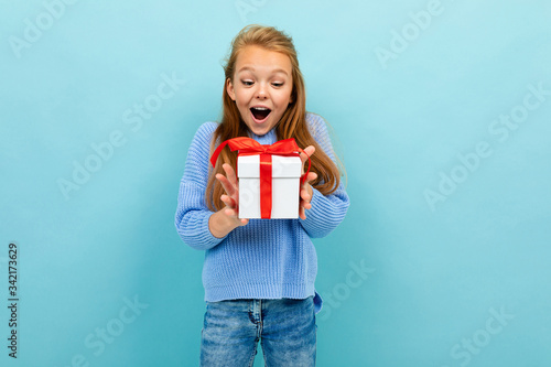 surprised european girl holding a gift on a light blue background