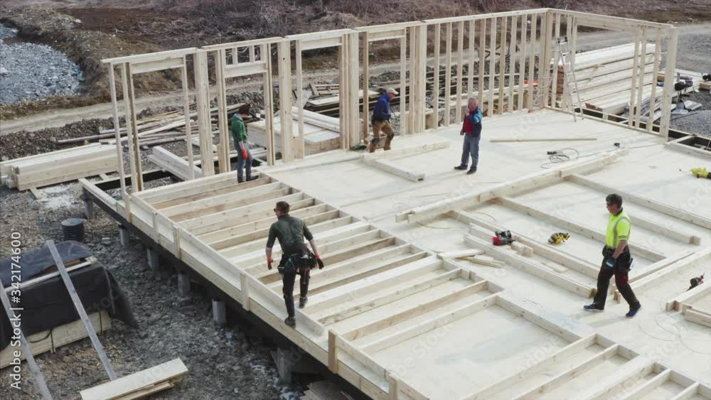 Aerial view of busy builders working at new frame house. Process of walls assembling Aerial view of busy builders working at new frame house. Process of walls assembling