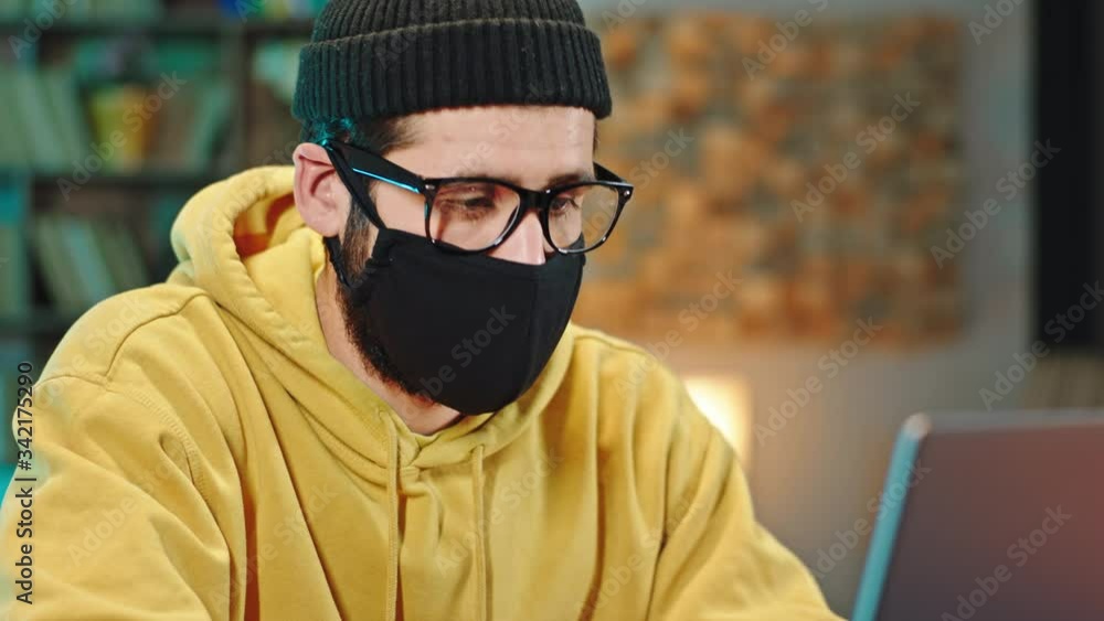 Portrait of a guy with a protective mask in front of the camera concentrated working on his laptop from home in his office Coronavirus pandemic 2019 China Portrait of a guy with a protective mask in front of the camera concentrated working on his laptop from home in his office Coronavirus pandemic 2019 China