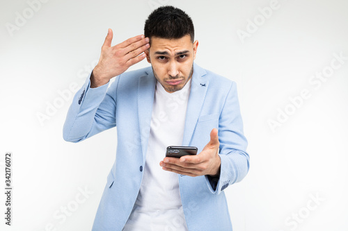 businessman twists at his temple and is surprised with information on the Internet holding a phone in red on a white background studio with copy space