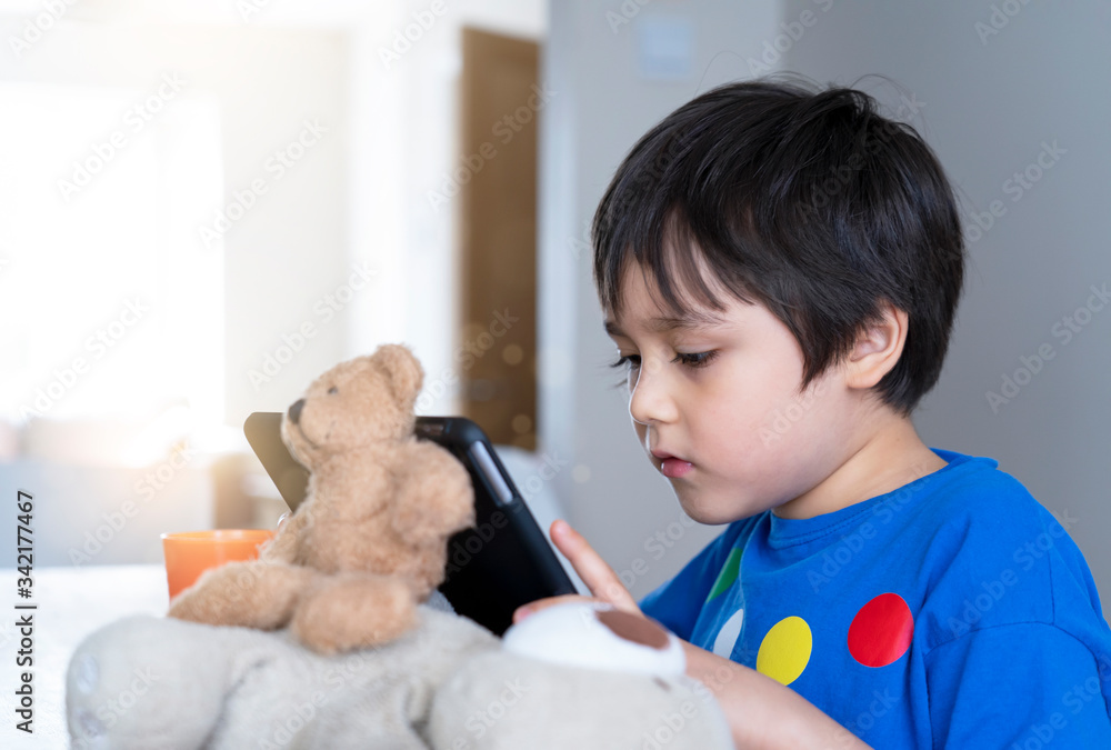 Kid self isolation using tablet for his homework,Child doing using digital tablet searching information on internet during covid-19 lock down,Social Distancing ,E-learning and online education Kid self isolation using tablet for his homework,Child doing using digital tablet searching information on internet during covid-19 lock down,Social Distancing ,E-learning and online education