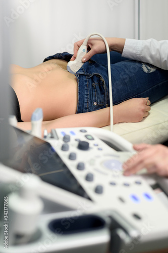 Female doctor working with ultrasound scanner examining her patient's belly in a modern clinic