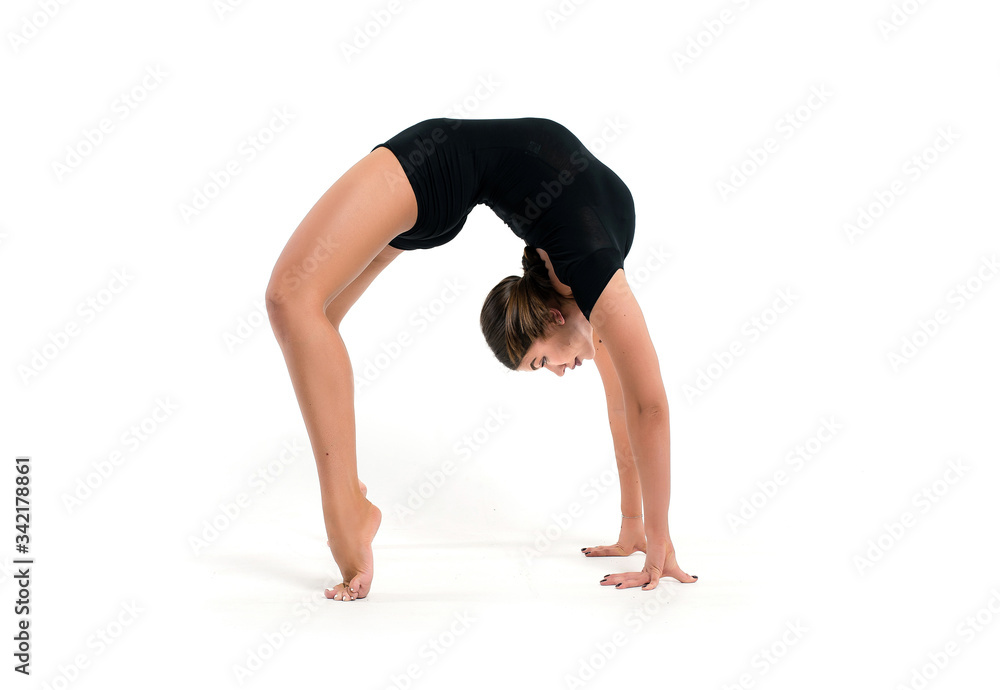 Beautiful athletic young girl gymnast in sportswear, training, element of gymnastics, performs exercises on a white background. Sports motivation, stretching, flexibility Beautiful athletic young girl gymnast in sportswear, training, element of gymnastics, performs exercises on a white background. Sports motivation, stretching, flexibility